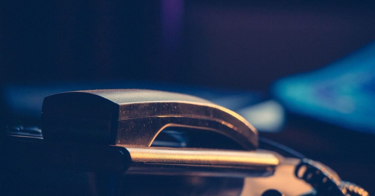 Téléphone de bureau posé sur un plan de travail sombre