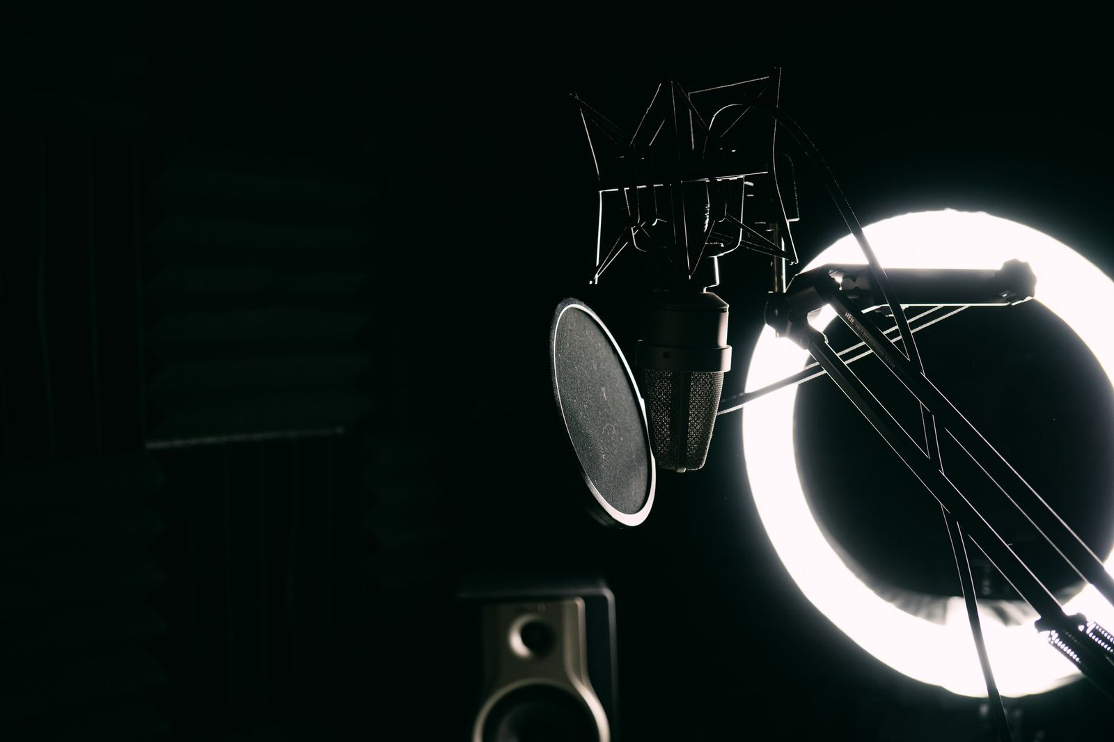 Microphone de studio avec filtre anti-pop et anneau lumineux dans une cabine d'enregistrement sombre