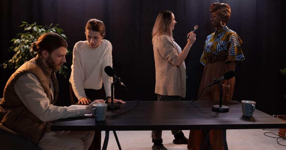 Plusieurs personnes d'origines diverses autour d'une table de studio équipée de micros avant un enregistrement