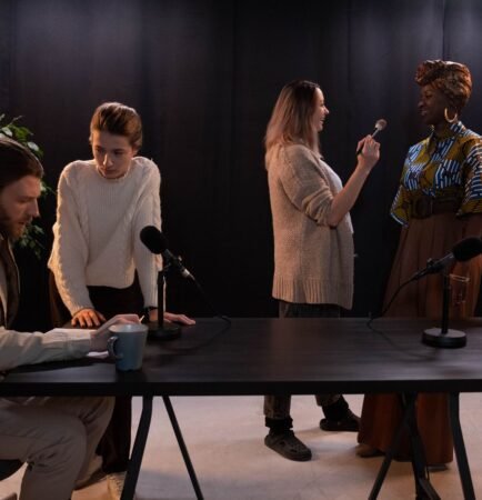 Plusieurs personnes d'origines diverses autour d'une table de studio équipée de micros avant un enregistrement