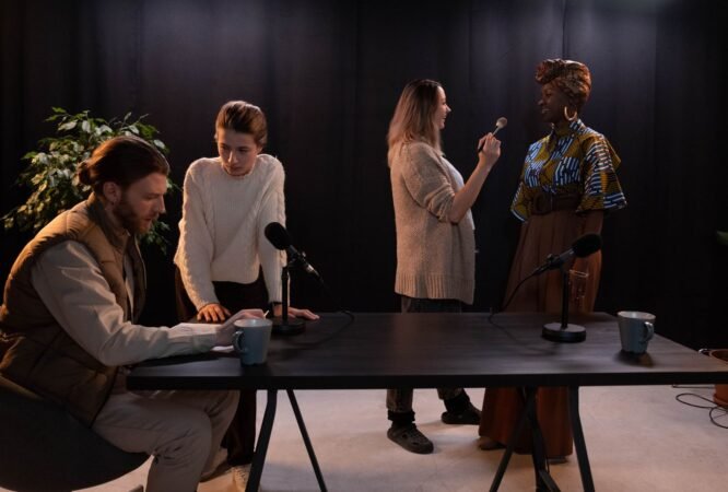 Plusieurs personnes d'origines diverses autour d'une table de studio équipée de micros avant un enregistrement